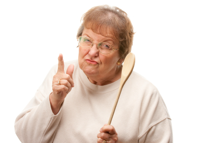 Upset Senior Woman with The Wooden Spoon Isolated on a White Background.